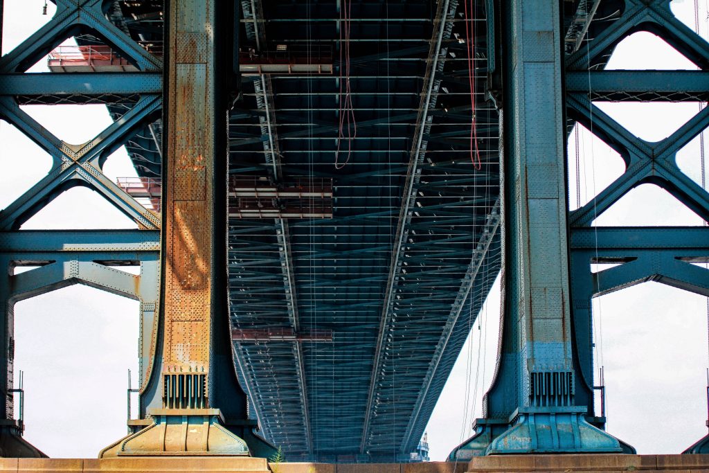 A low angle shot of a big blue metal bridge on a sunny day