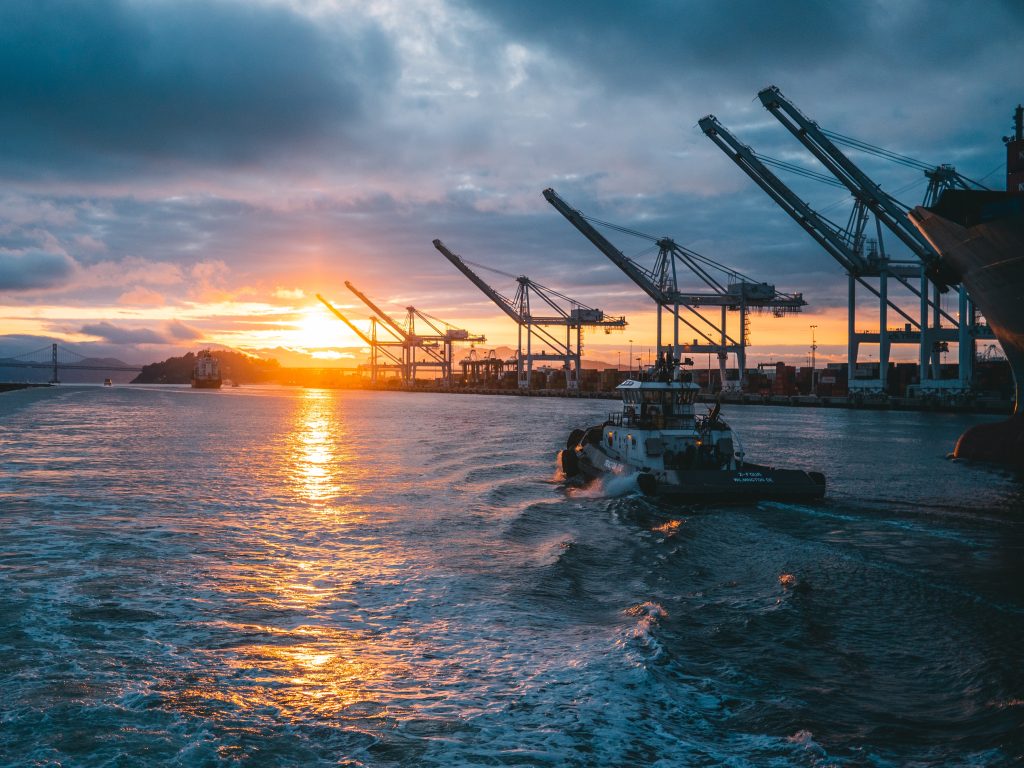 a panoramic shot of oil rigs at sea with a beautiful sunset in the background, under cloudy sky