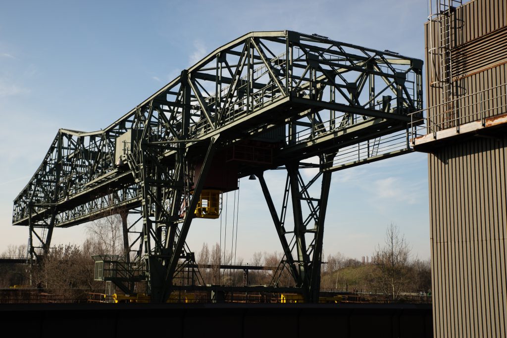 A wide shot of a huge metal structure and a building with a clear blue sky